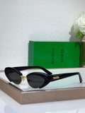 Bottega Veneta sunglasses with black frames, oval dark lenses, and gold accents