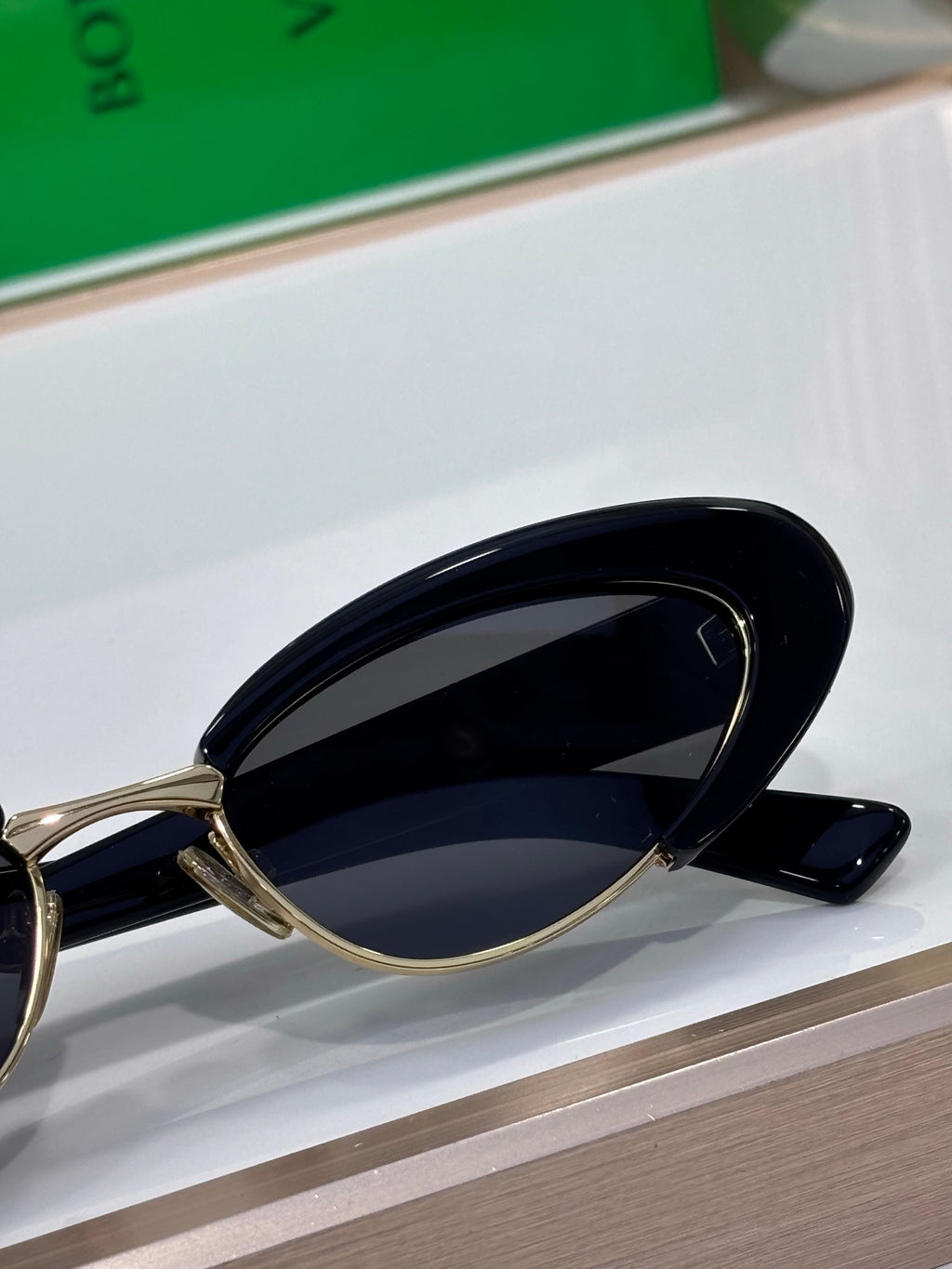 Bottega Veneta sunglasses close-up with black lenses and gold metal temple arms