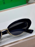 Bottega Veneta sunglasses close-up with black lenses and gold metal temple arms