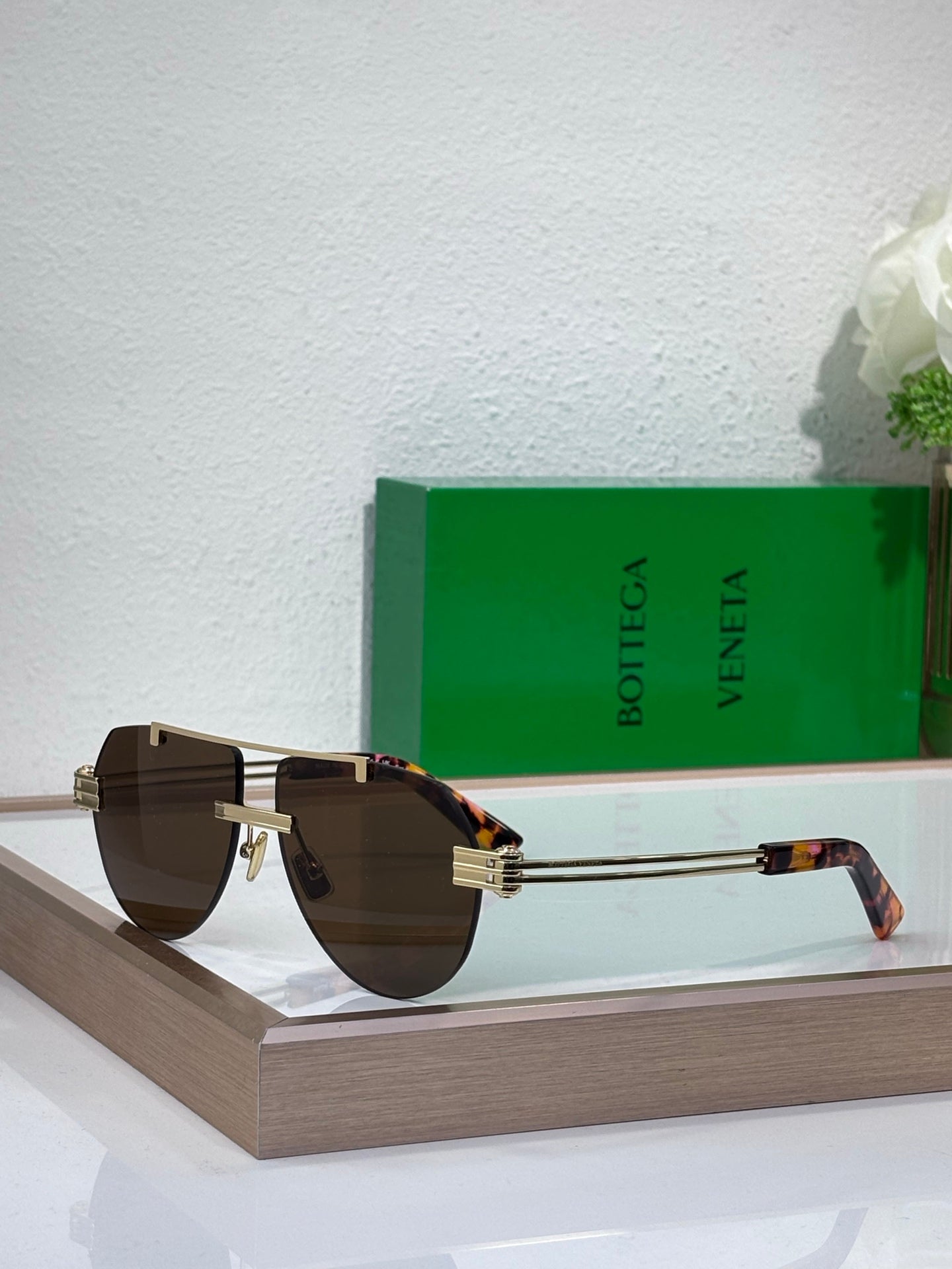 Sunglasses with brown gradient lenses and gold-tone metal frame, tortoise temples