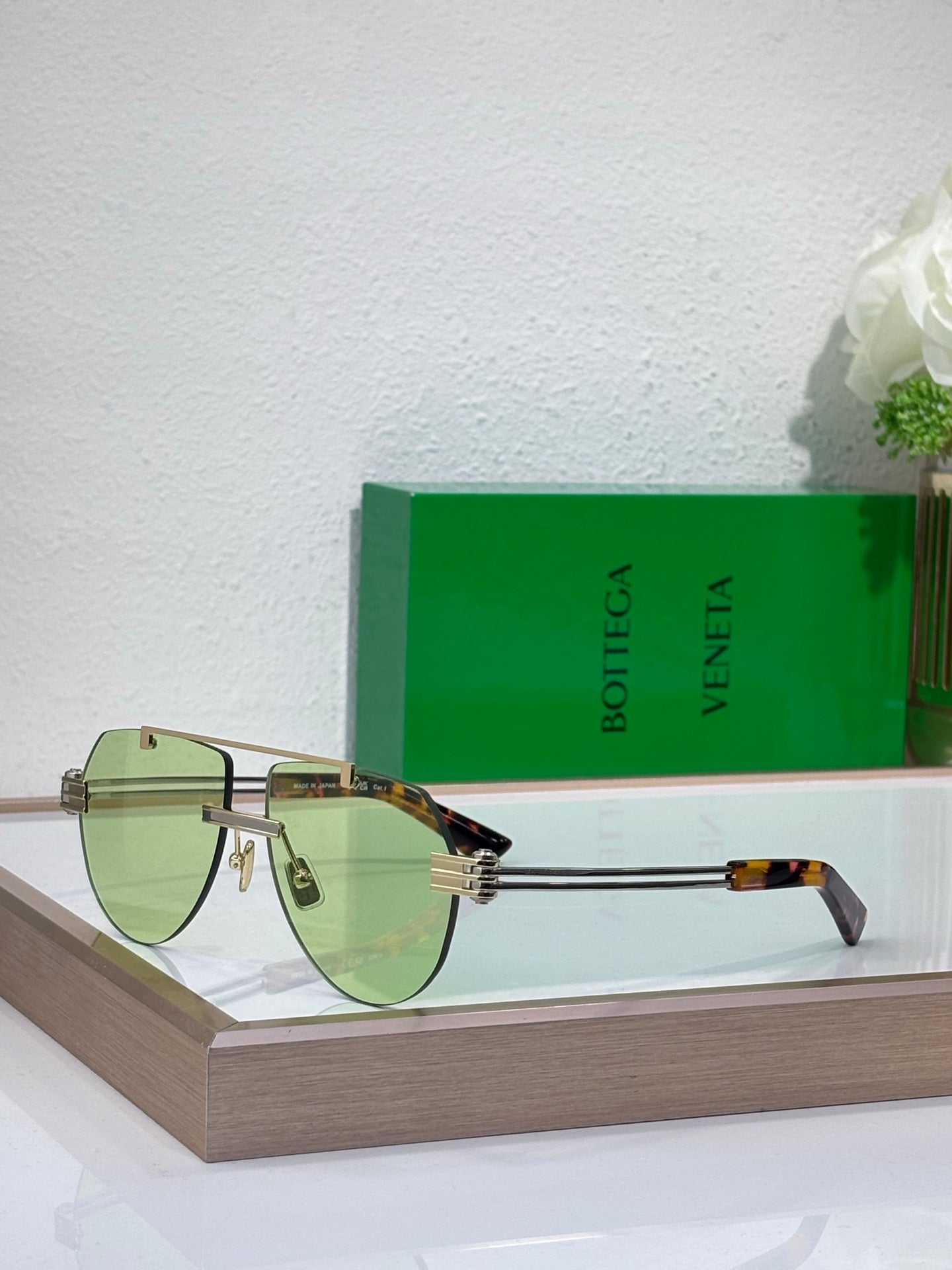 Sunglasses with light green gradient lenses and gold-tone metal frame, tortoise temples