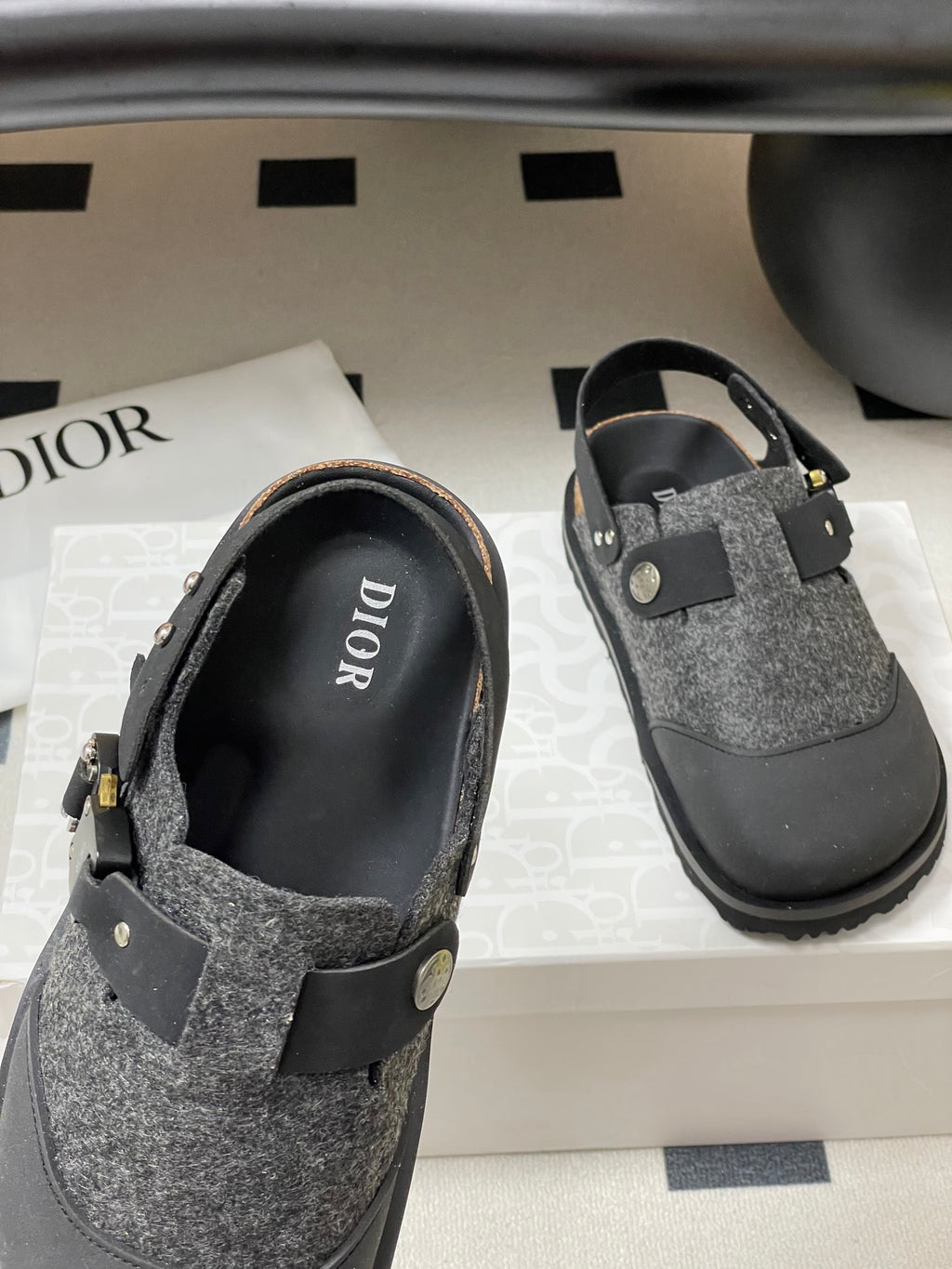 Dior sandals angled view with gray textured upper, black strap, and metal accent hardware