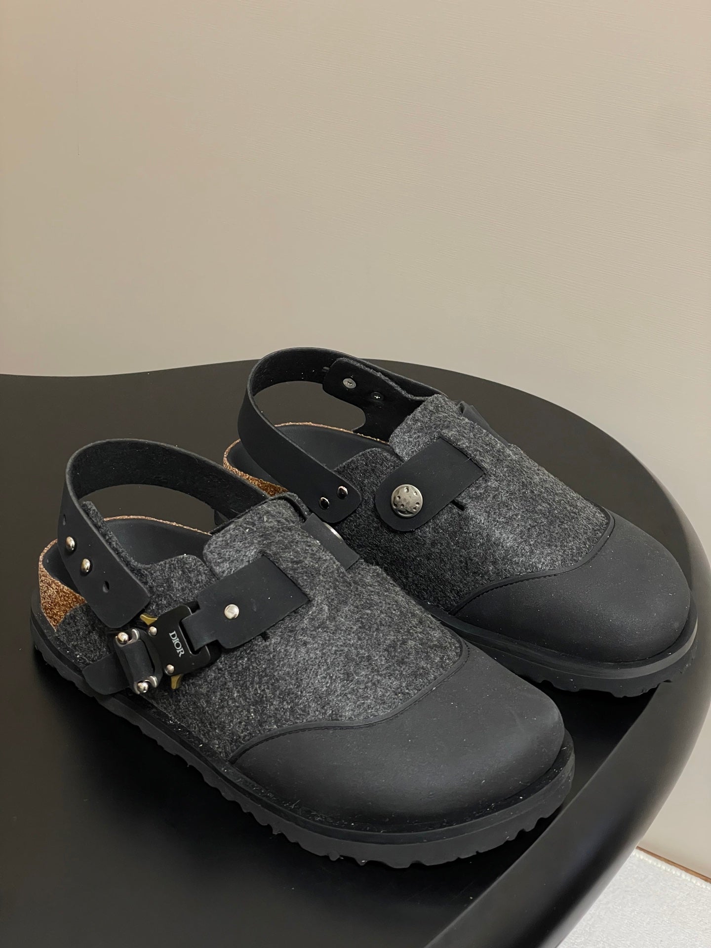 Dior mule sandals with gray textured upper, black straps, and gold-toned hardware