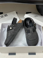 Dior mule sandals with gray speckled upper, black strap, round emblem, and gold studs