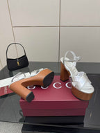 Gucci white platform heeled sandals and black mini handbag on display