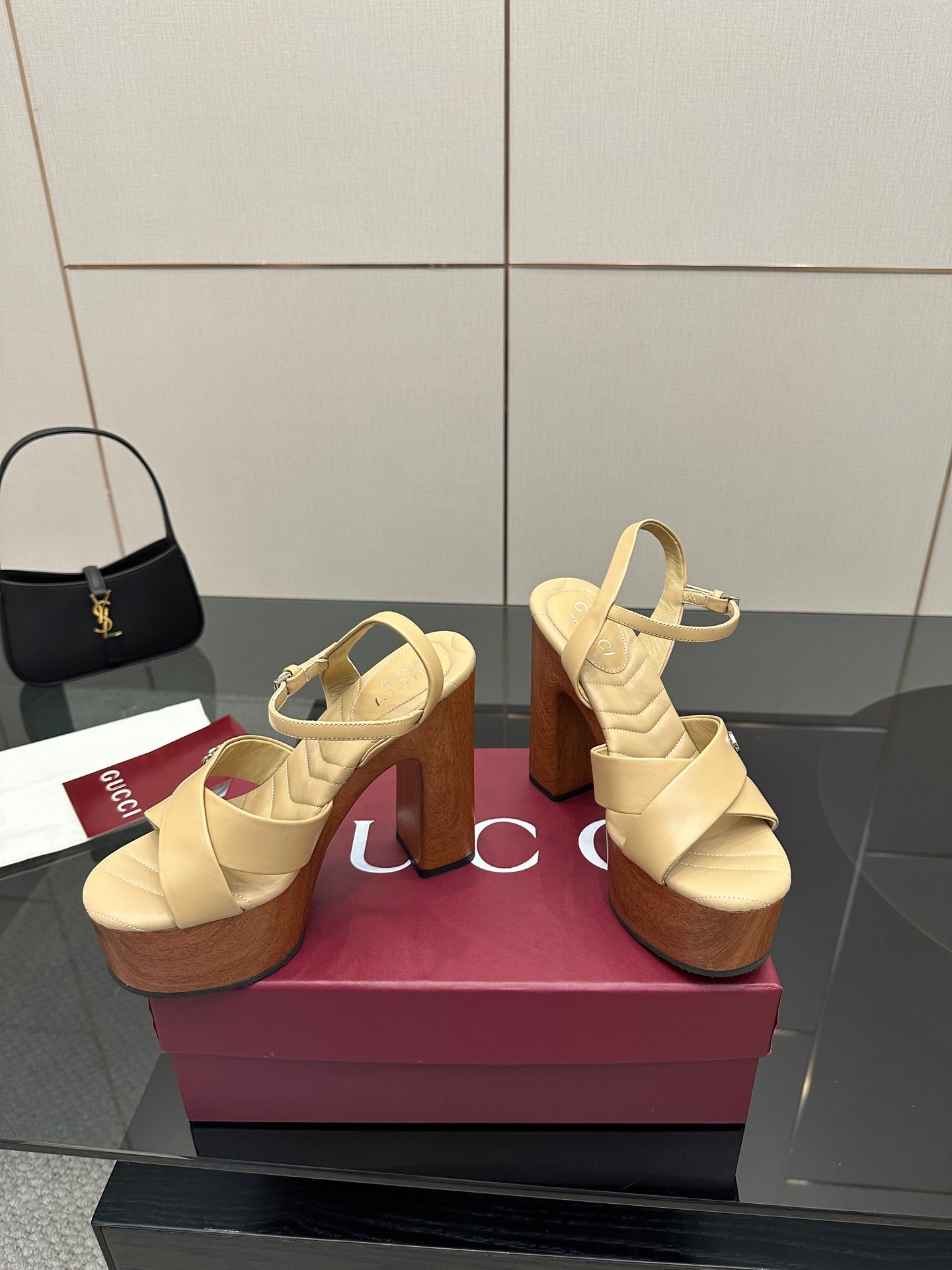 Gucci women's platform sandals pair on display, cream straps with cork platform and high heels.
