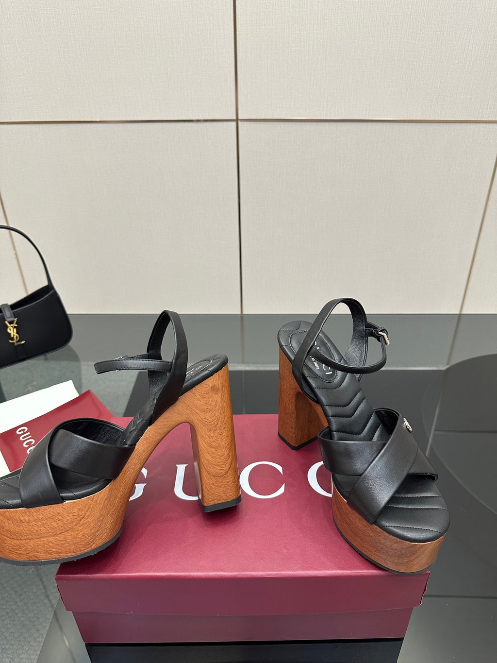 Gucci black platform heeled sandals showing front and side views with wood-look heels