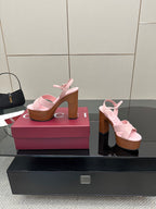Pink platform sandals with thick straps and wooden heels, two views on a box
