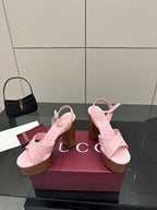 Pink platform sandals with X-style straps and chunky wooden heels on a display box