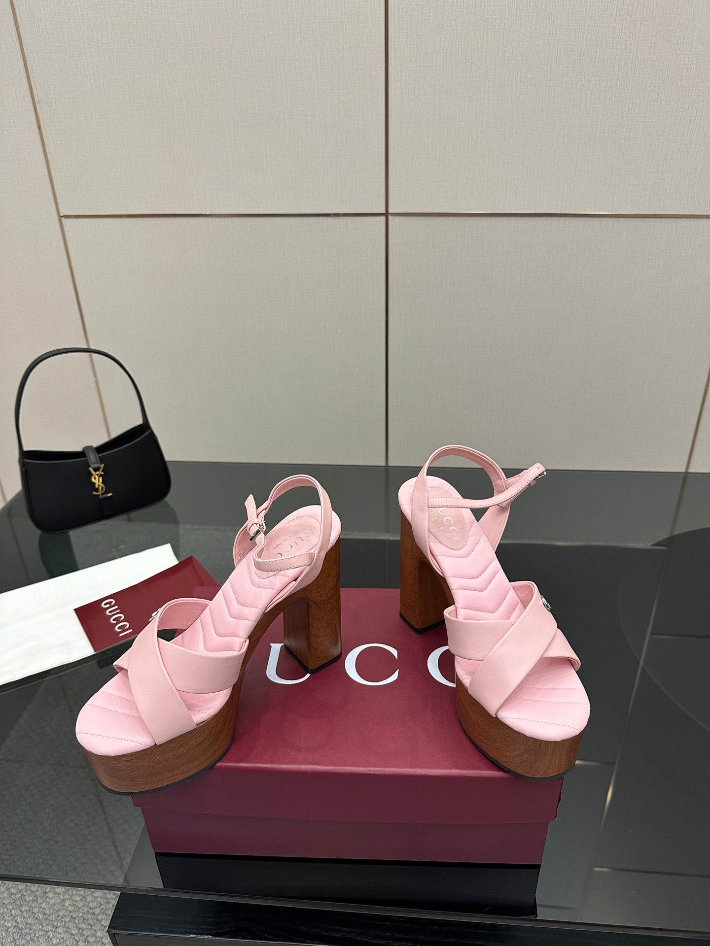 Pink platform sandals with X-style straps and chunky wooden heels on a display box