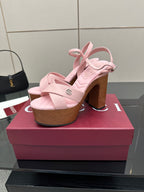 Pink platform sandals with ankle strap and chunky wooden block heels, front angle