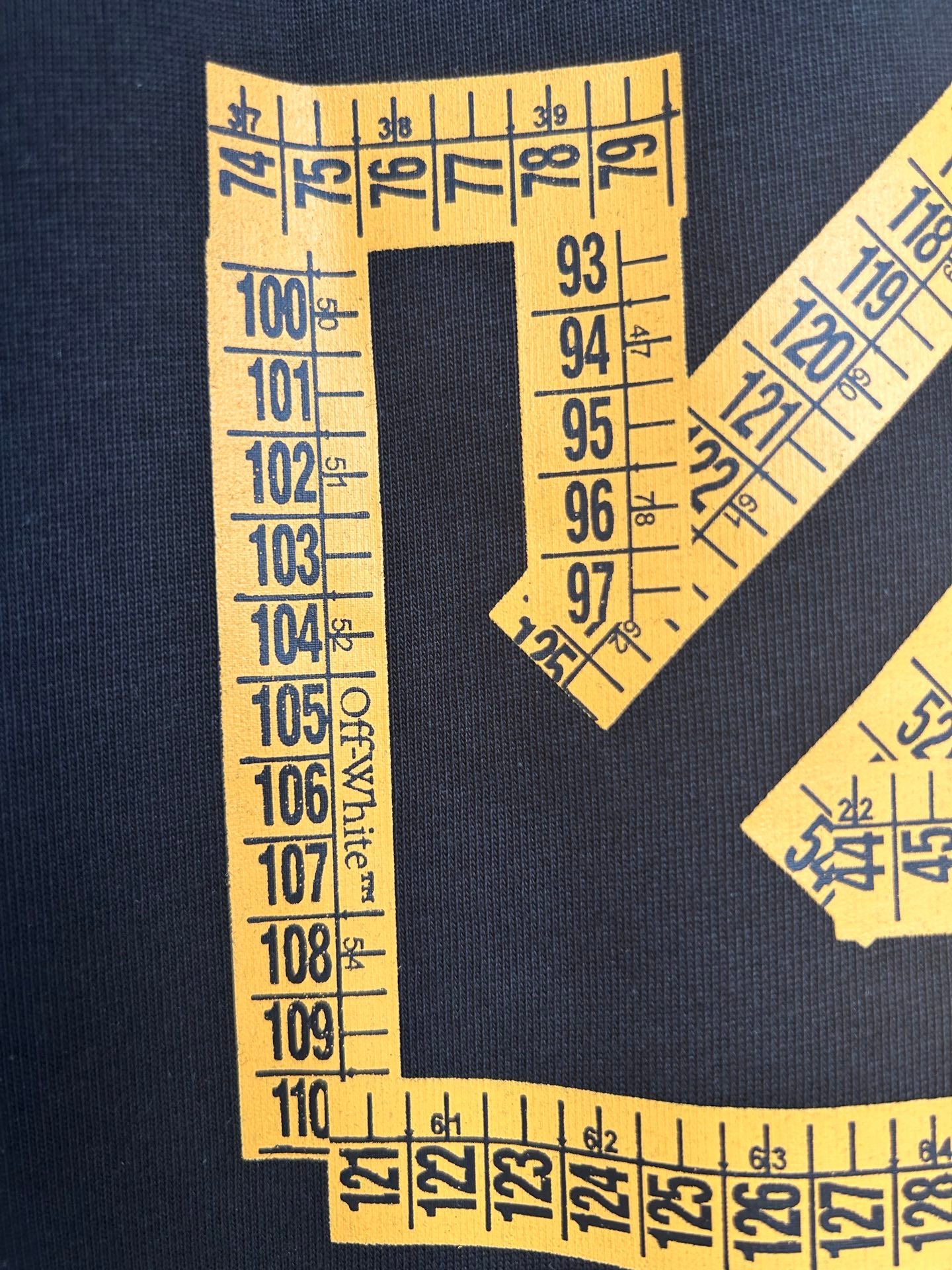 Yellow ruler-tape arrow graphic and numbers on dark T-shirt