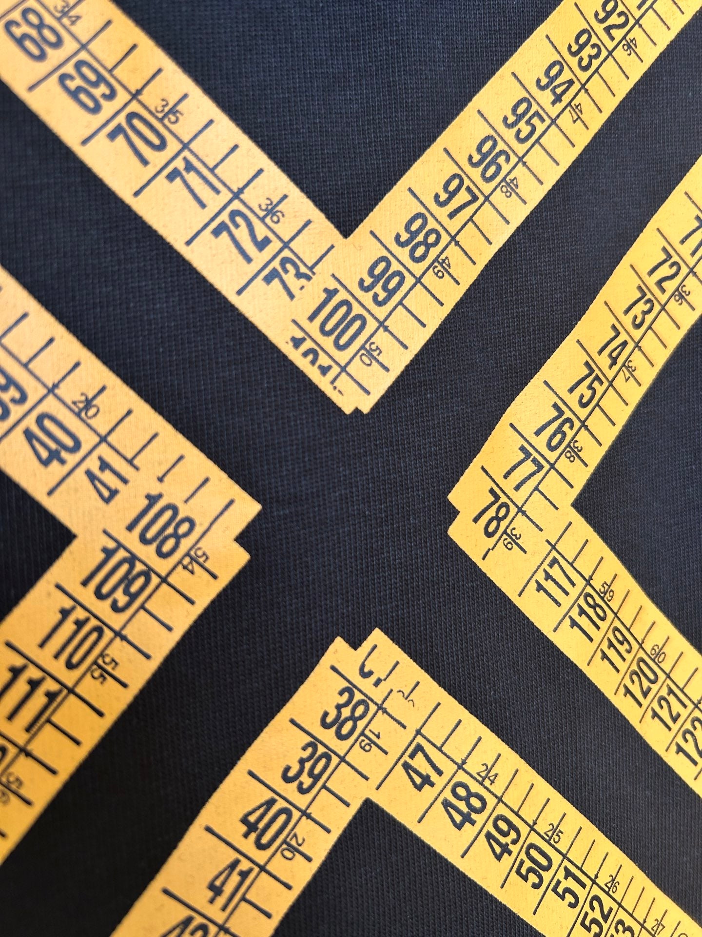 Yellow ruler-tape V and X graphic on dark T-shirt
