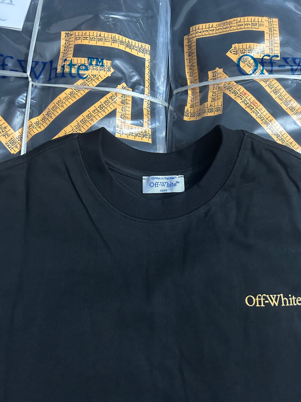 Off-White crewneck T-shirt with small gold Off-White logo on dark fabric
