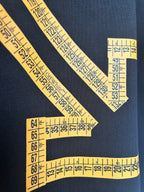 Yellow ruler-tape arrow graphic detail on dark T-shirt