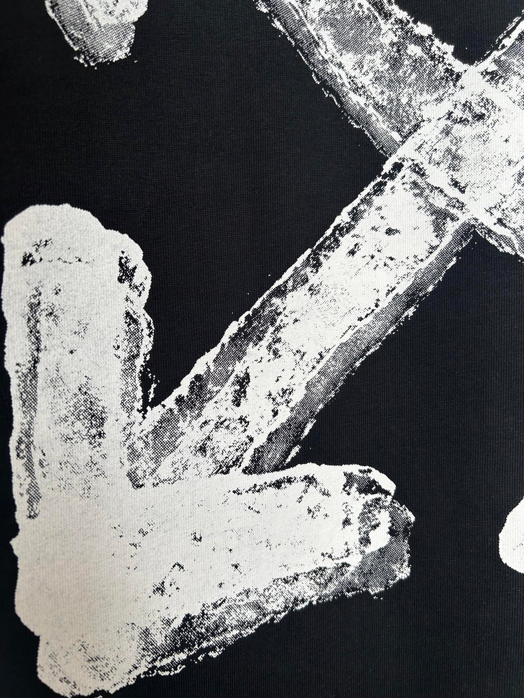 Black T-shirt close-up of off-white distressed left arrow graphic
