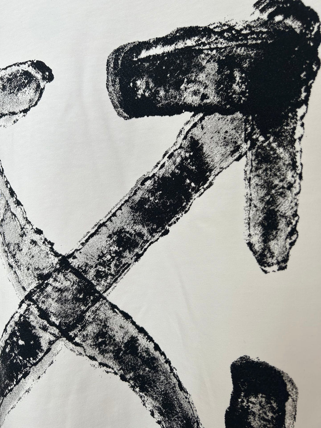 Off-white T-shirt close-up of black logo X and letter strokes