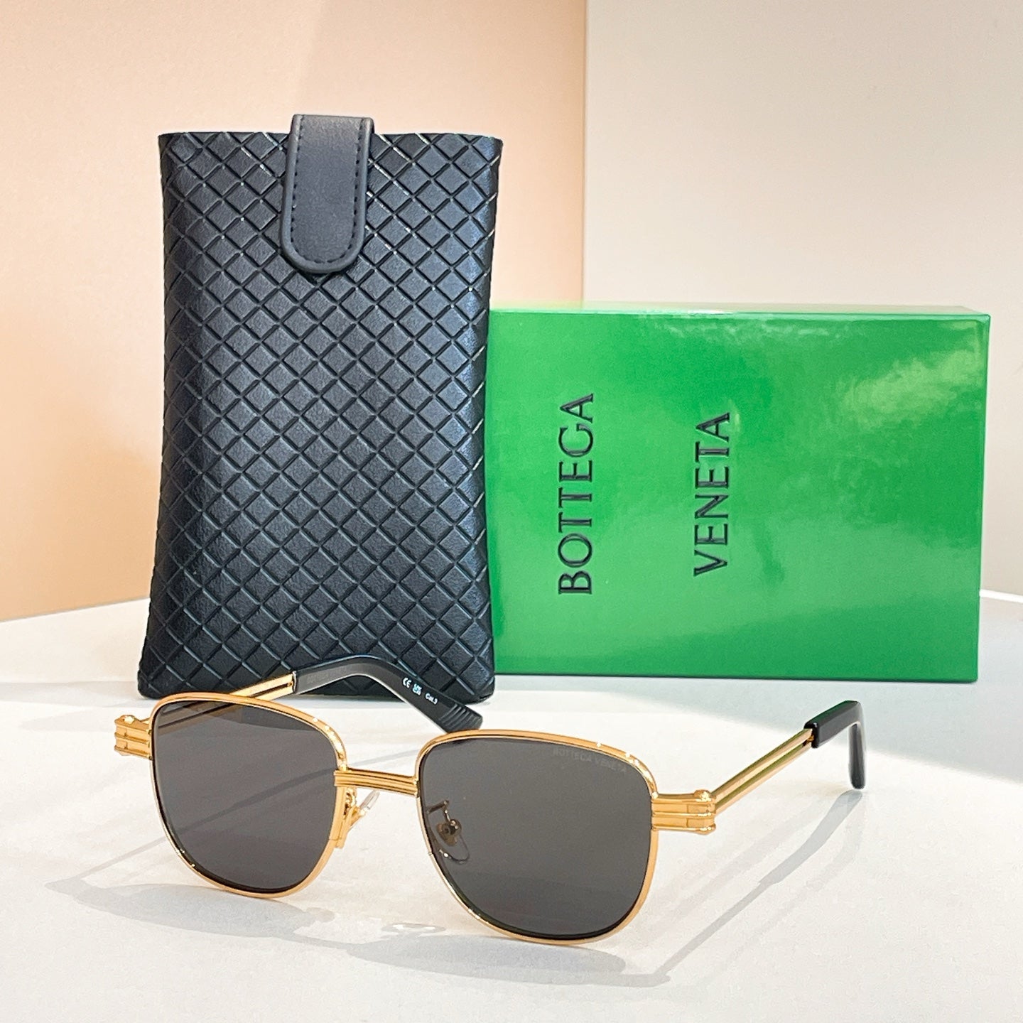 Bottega Veneta sunglasses with dark lenses, gold-tone round frame and extended arms.