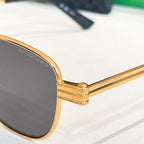 Bottega Veneta sunglasses hinge detail with gold-tone bar and dark oval lens.