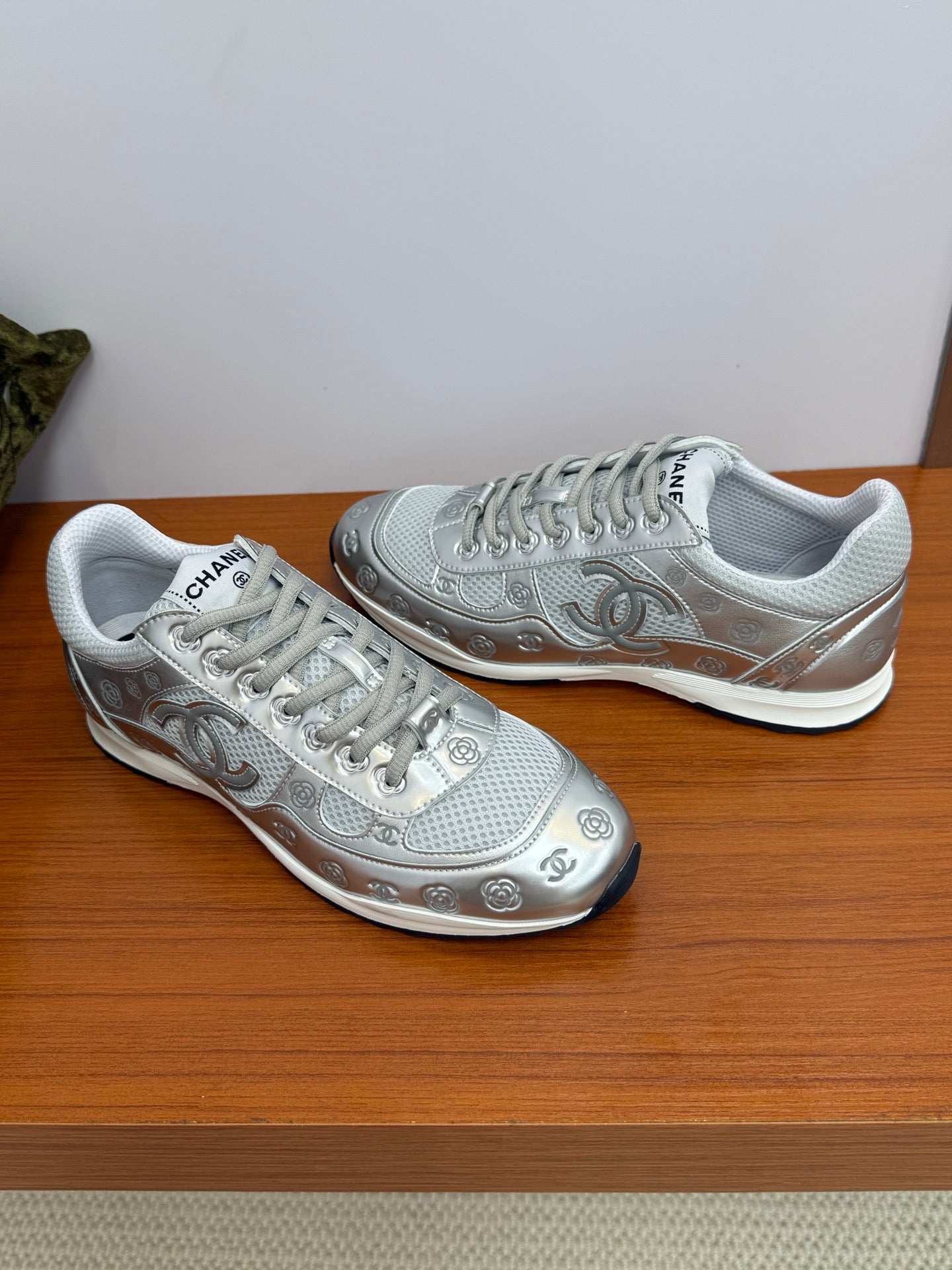 Gray Chanel logo sneakers, side-by-side angle showing swoosh-like motif and laces