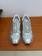 Gray low-top sneakers with white laces and Chanel logo print on the toe and sides