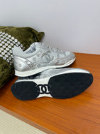 Gray Chanel logo sneakers with visible outsole, tread and signature CC on the heel
