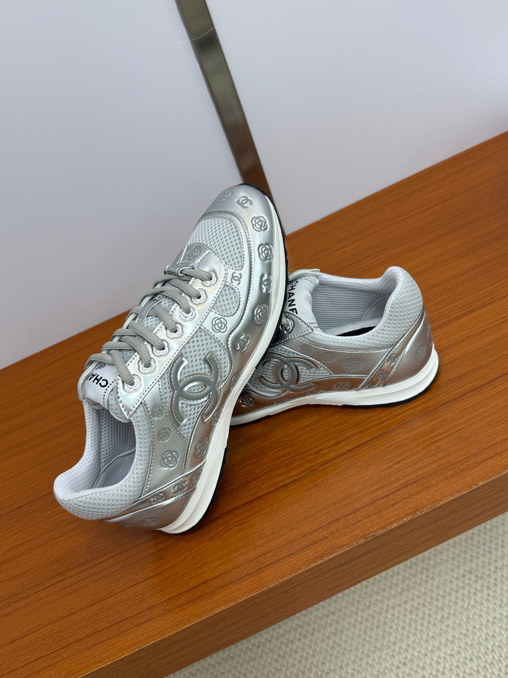 Gray Chanel logo sneakers, angled view showing side panels, laces, and chunky sole