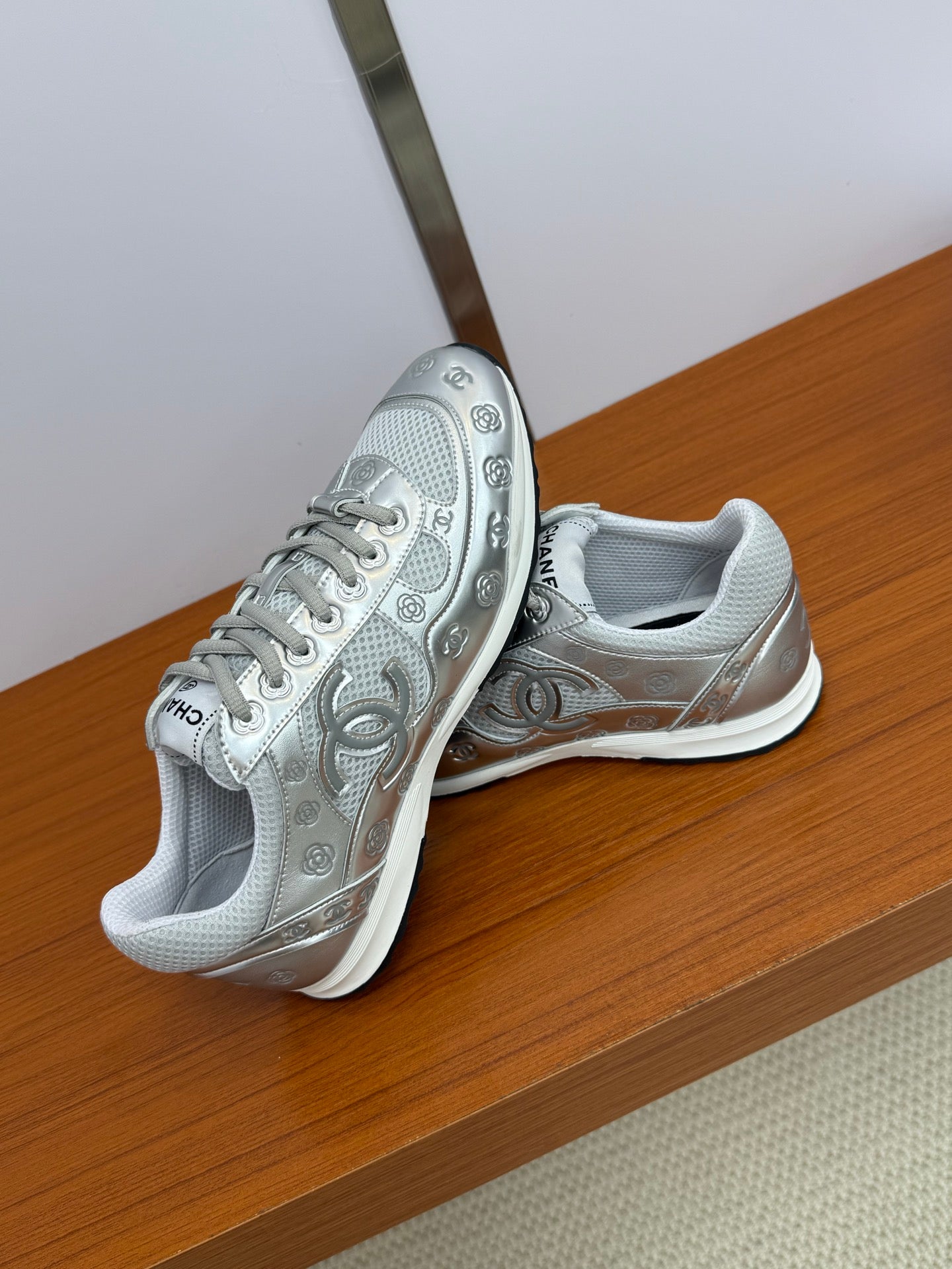 Gray Chanel logo sneakers, angled view showing side panels, laces, and chunky sole