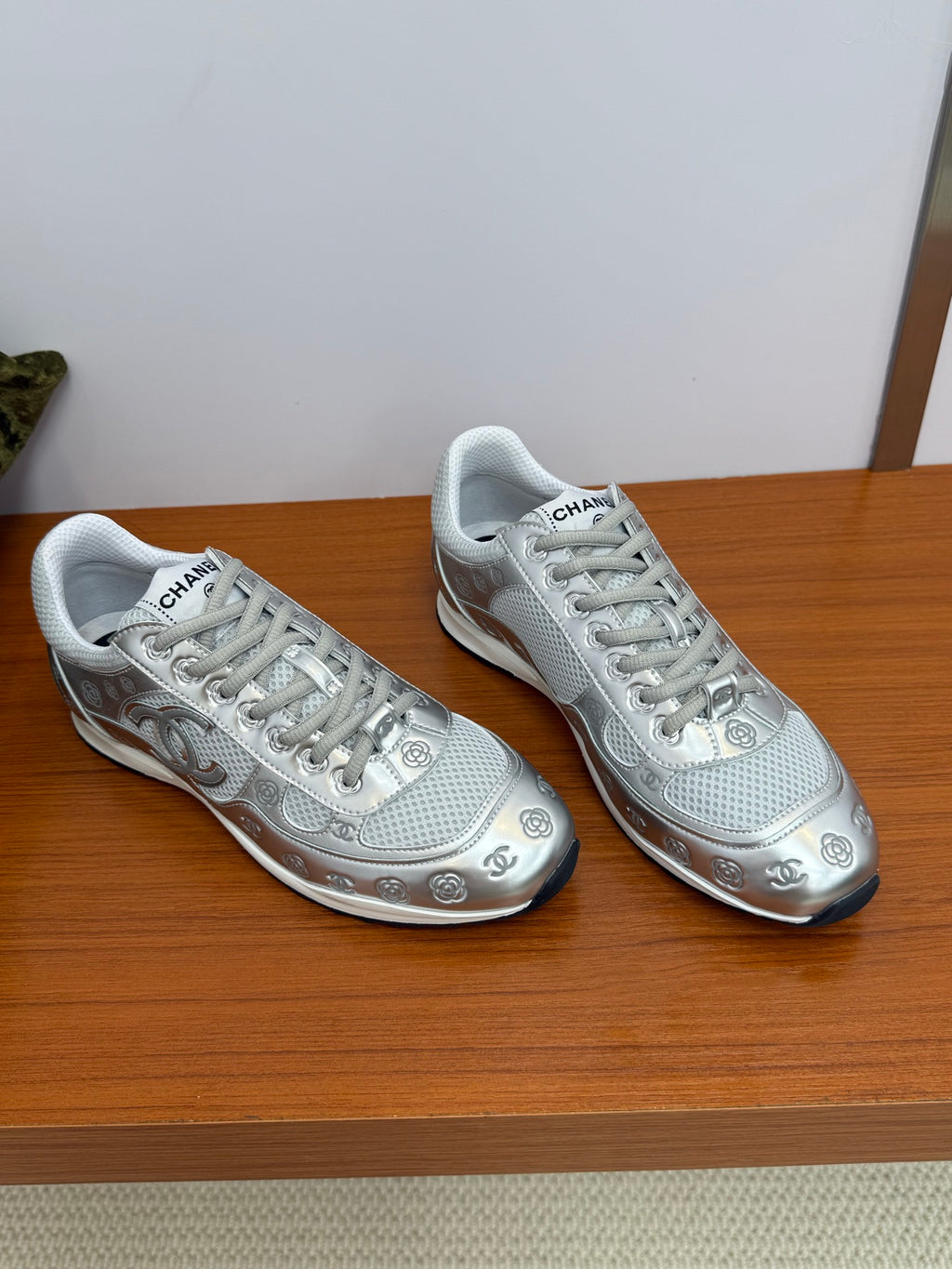Pair of gray Chanel logo sneakers, front-facing view with white laces and toe caps