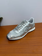 Gray low-top Chanel logo sneakers, angled view showing lace-up front and side motifs