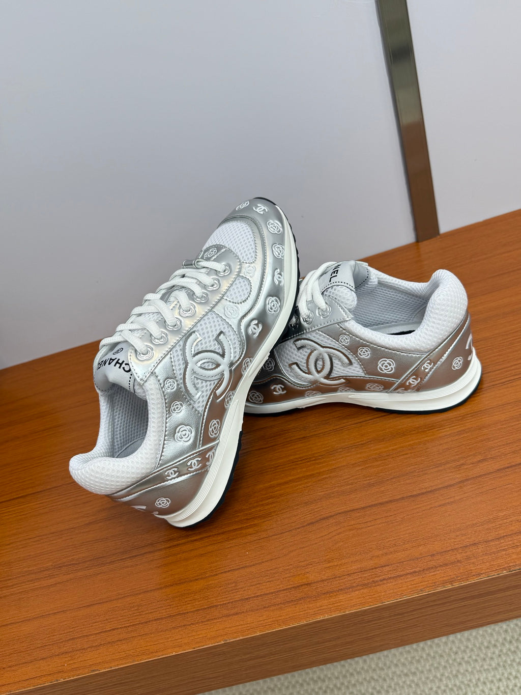 Chanel white low-top sneakers with logo trim, seen from a low side angle.