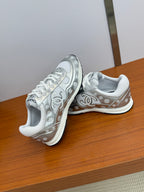Chanel white low-top sneakers with logo trim, seen from a low side angle.