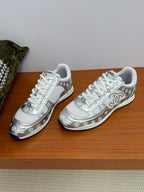 Chanel white low-top sneakers side-by-side, patterned logo details and white laces.