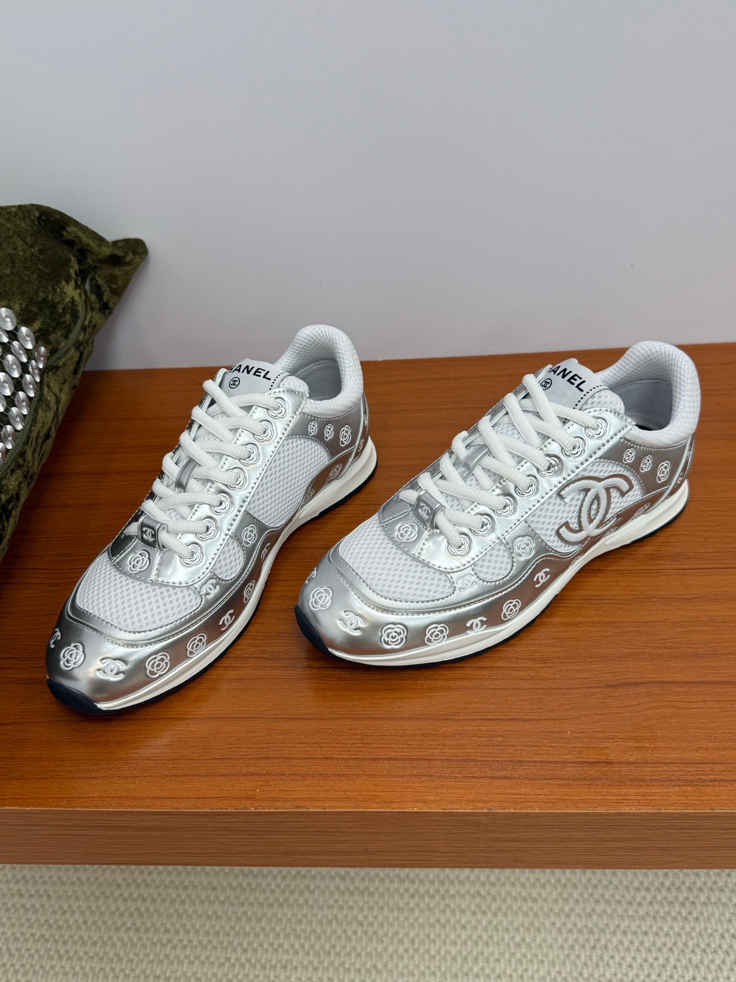Chanel white low-top sneakers side-by-side, patterned logo details and white laces.
