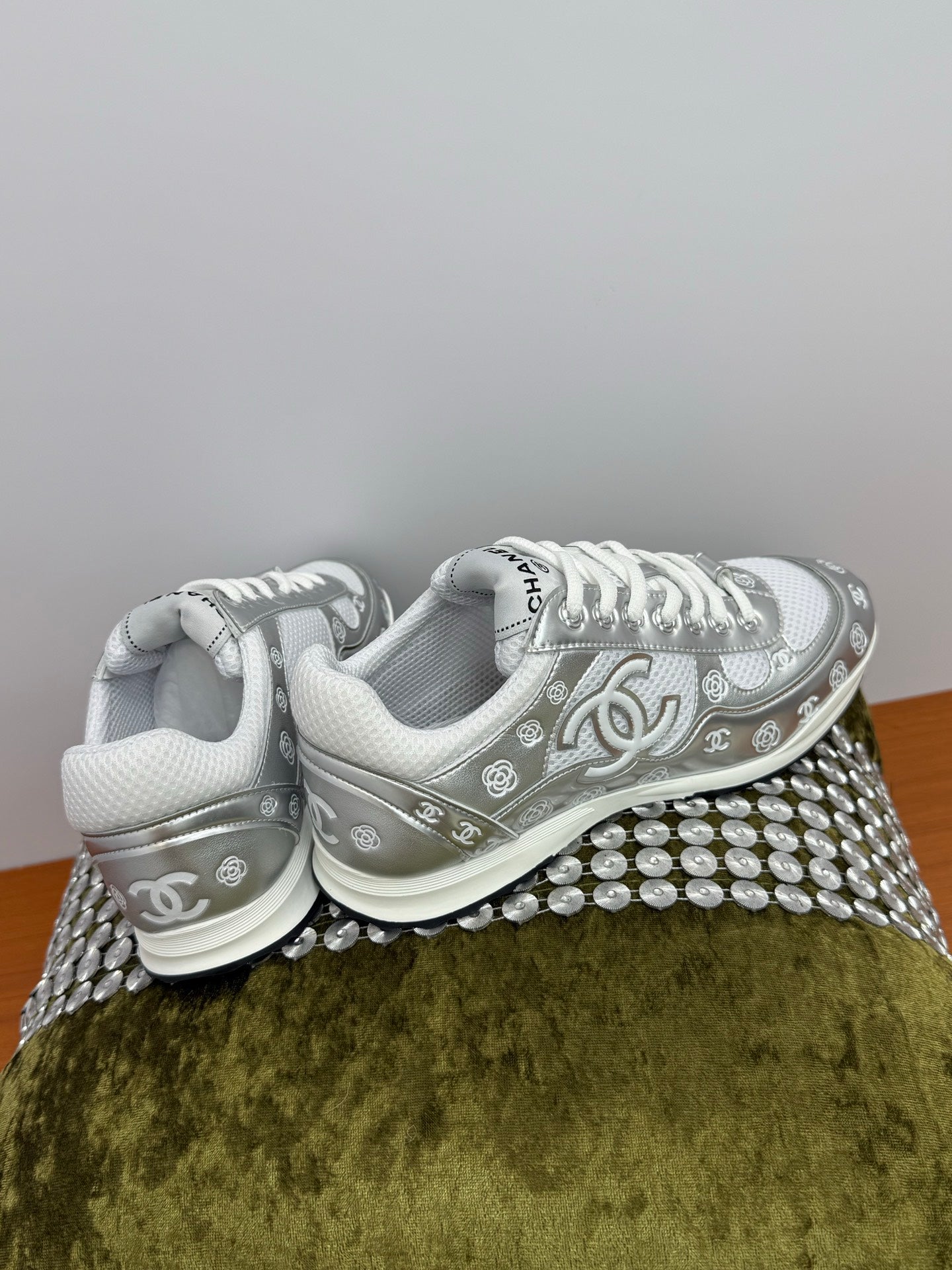 Chanel white low-top sneakers with logo trim and studded, textured platform edge.