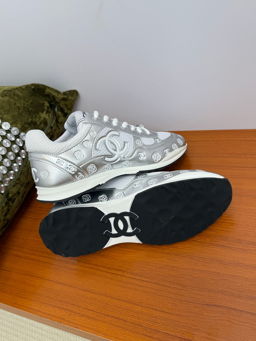 Chanel white low-top sneakers with studded trim; black outsole with logo.