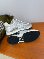 Chanel white low-top sneakers with studded trim; black outsole with logo.