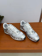 Pair of Chanel white low-top sneakers with patterned trim and white laces.