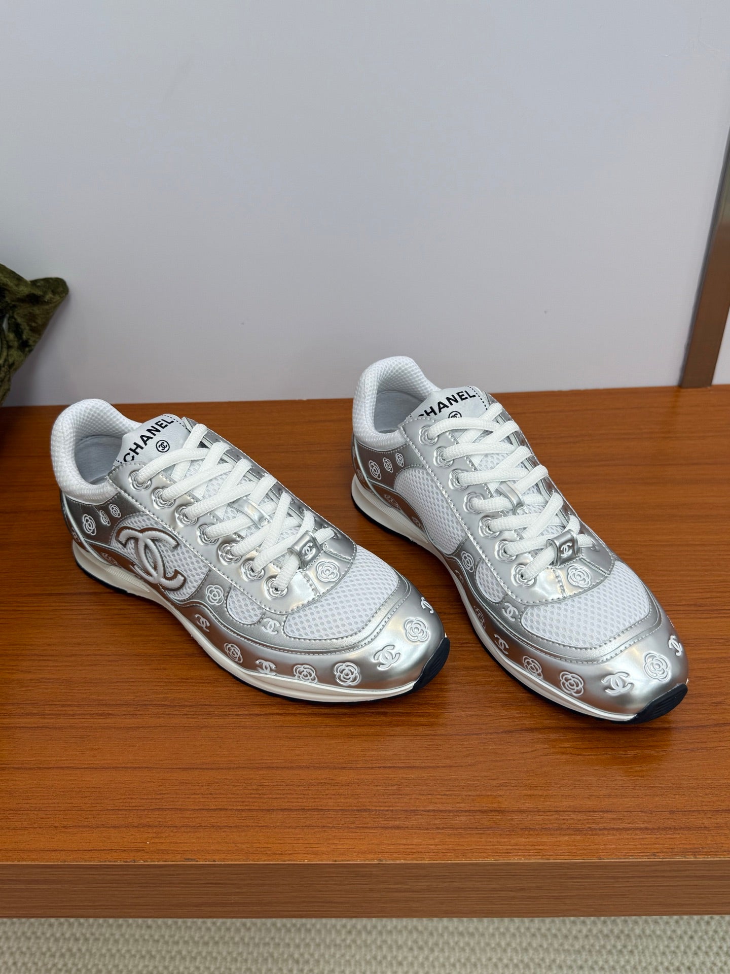 Pair of Chanel white low-top sneakers with patterned trim and white laces.