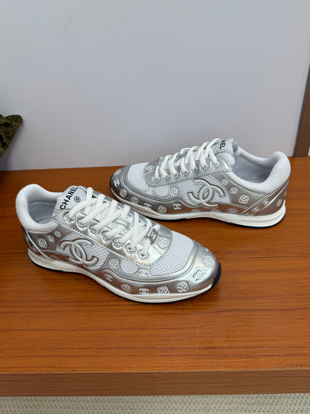 Chanel white low-top sneakers, angled side view with logo trim and textured sole.