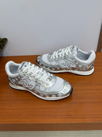 Chanel white low-top sneakers, angled side view with logo trim and textured sole.