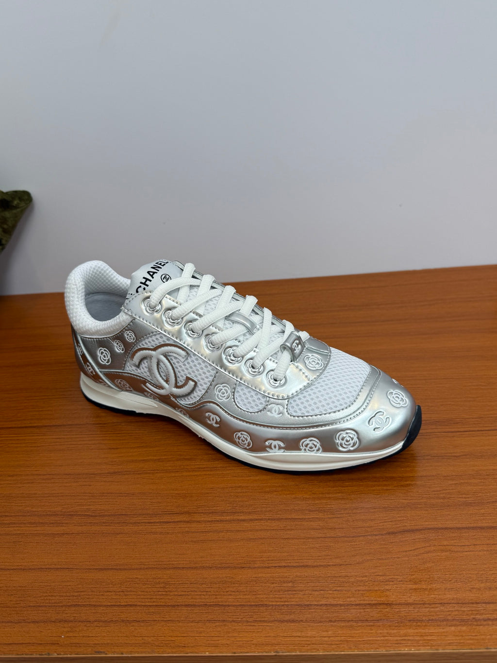 Chanel white low-top sneaker, side view with logo trim and white lace-up.