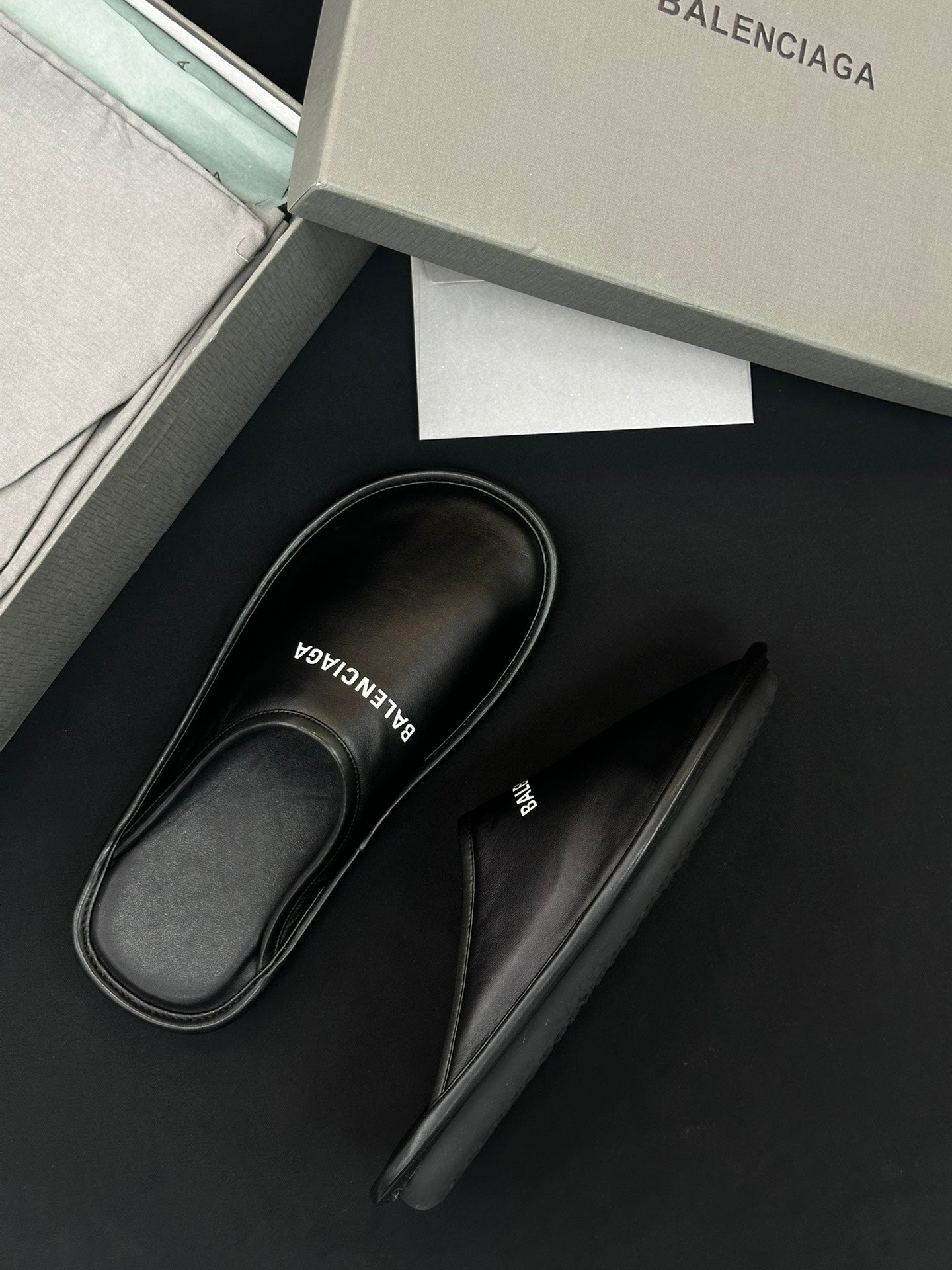 Black leather slides with BALENCIAGA logo on insole, one pair view