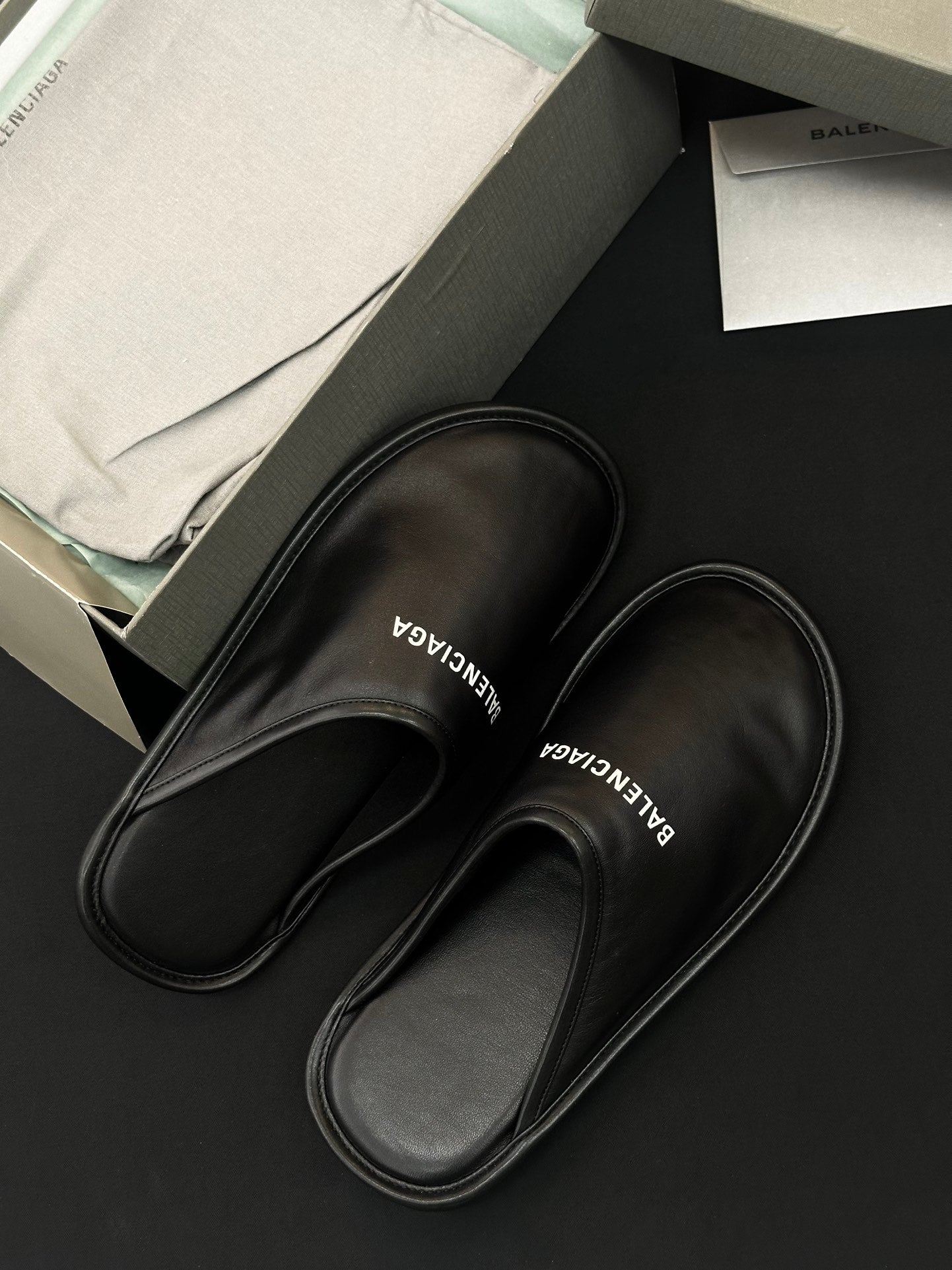 Black leather slides with BALENCIAGA logo on insole, close-up angle