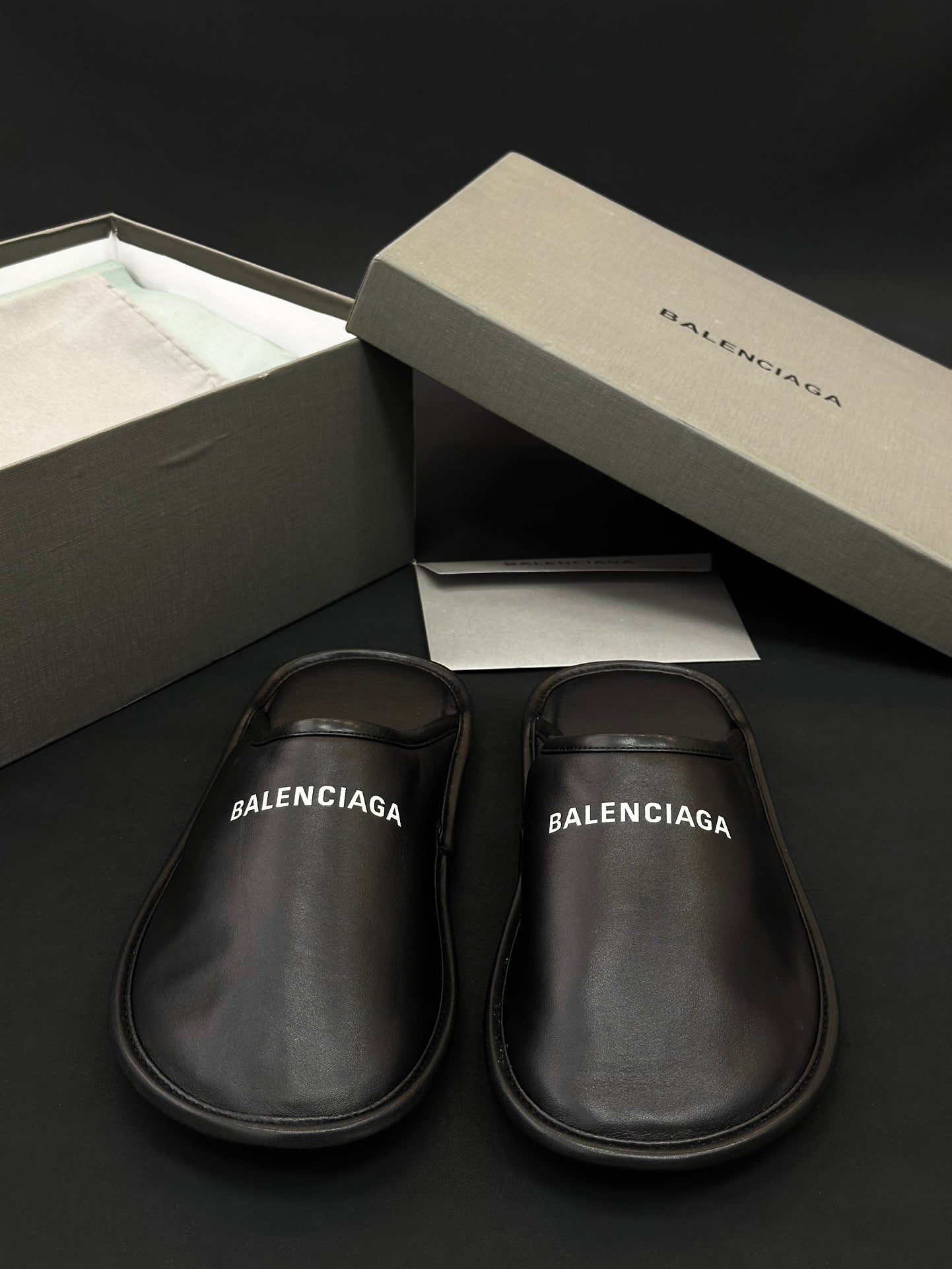 Black leather slides, BALENCIAGA logo print on footbed, side-by-side