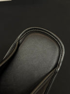 Black leather slide toe area close-up with stitched edge detail