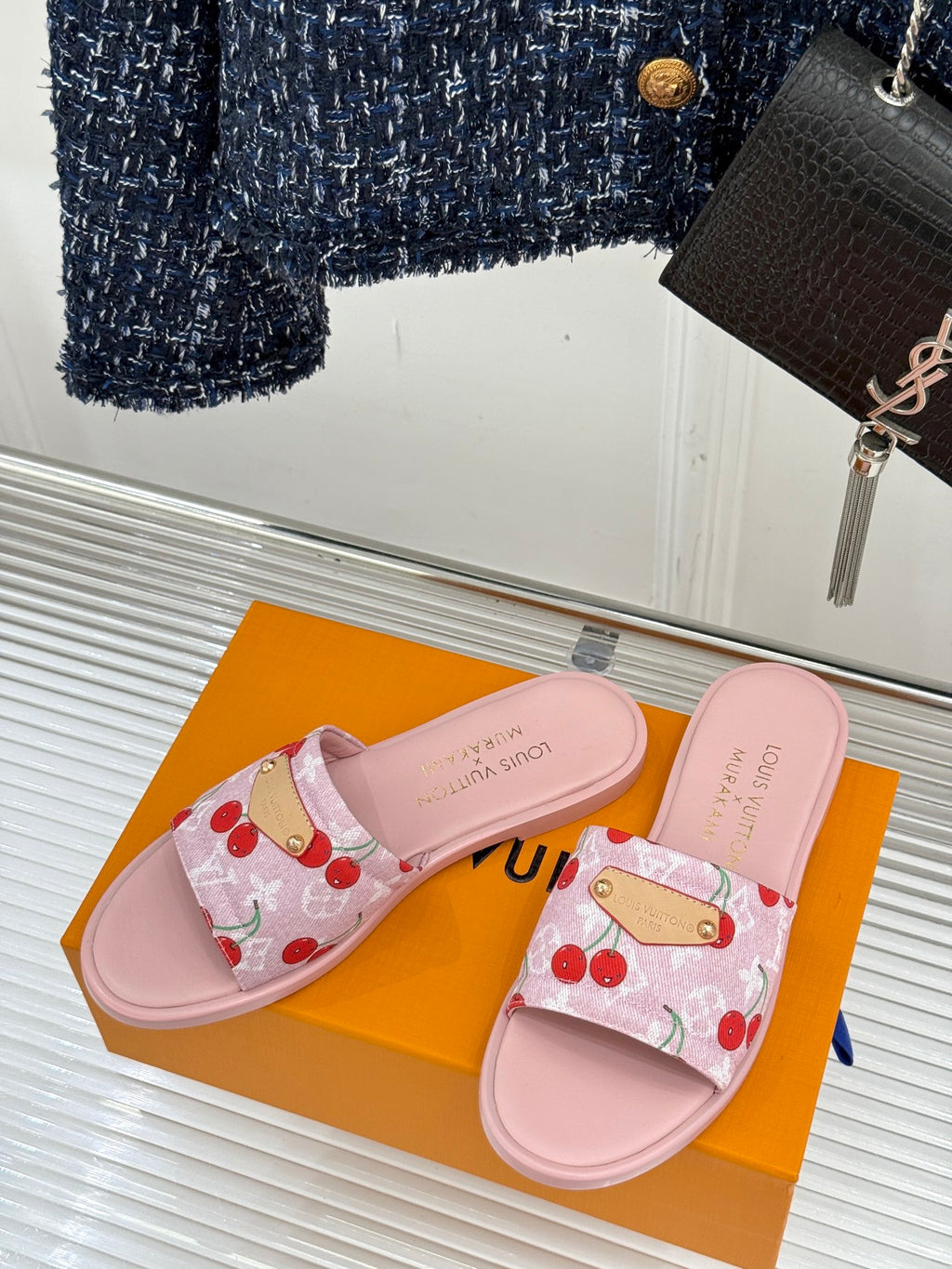 Pink cherry-pattern slide sandals on a display with gold-tone strap hardware