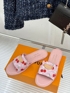 Pink cherry-pattern slide sandals on a display with gold-tone strap hardware