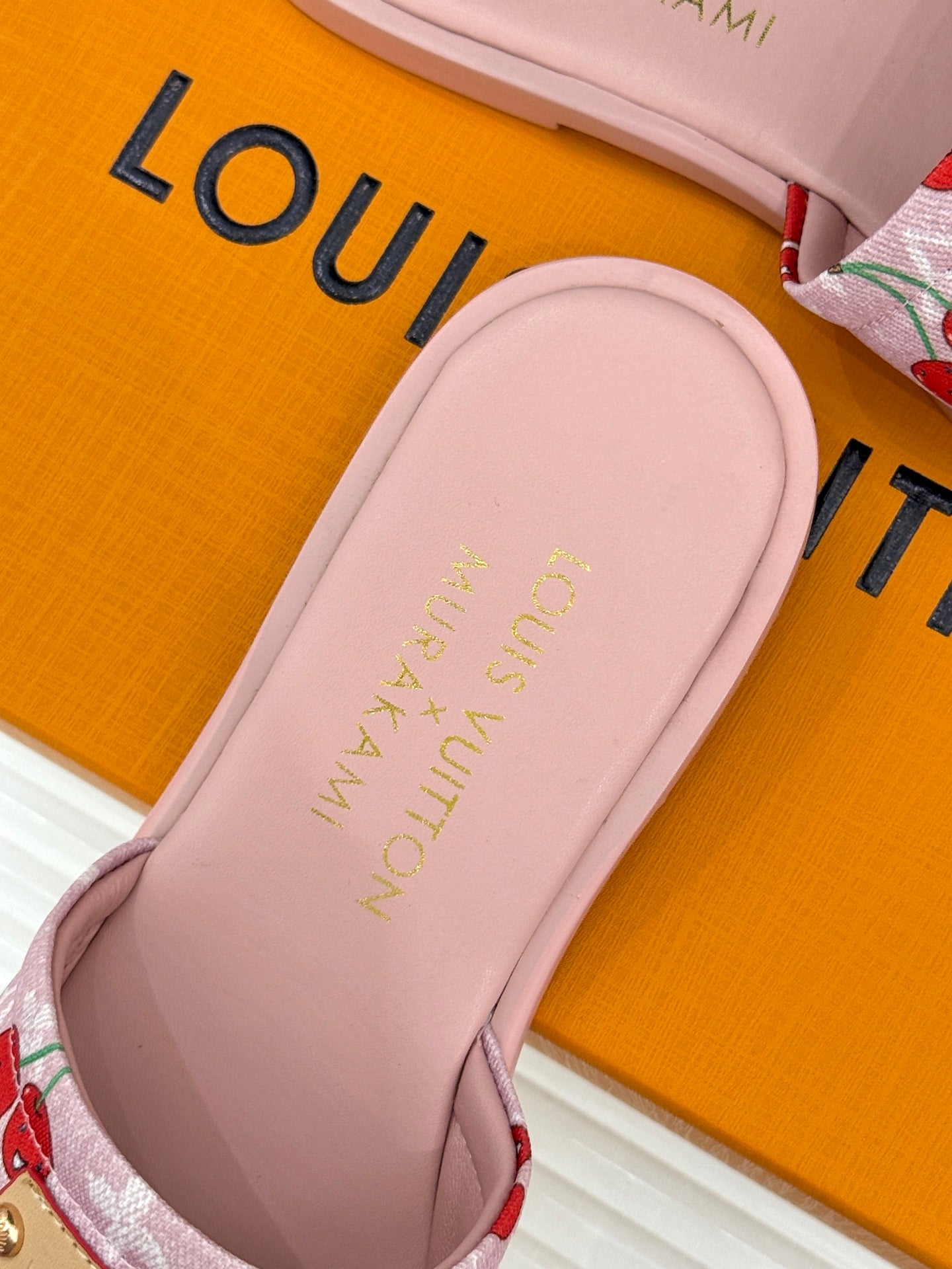 Close-up of pink slide sandal with embossed logo text on footbed