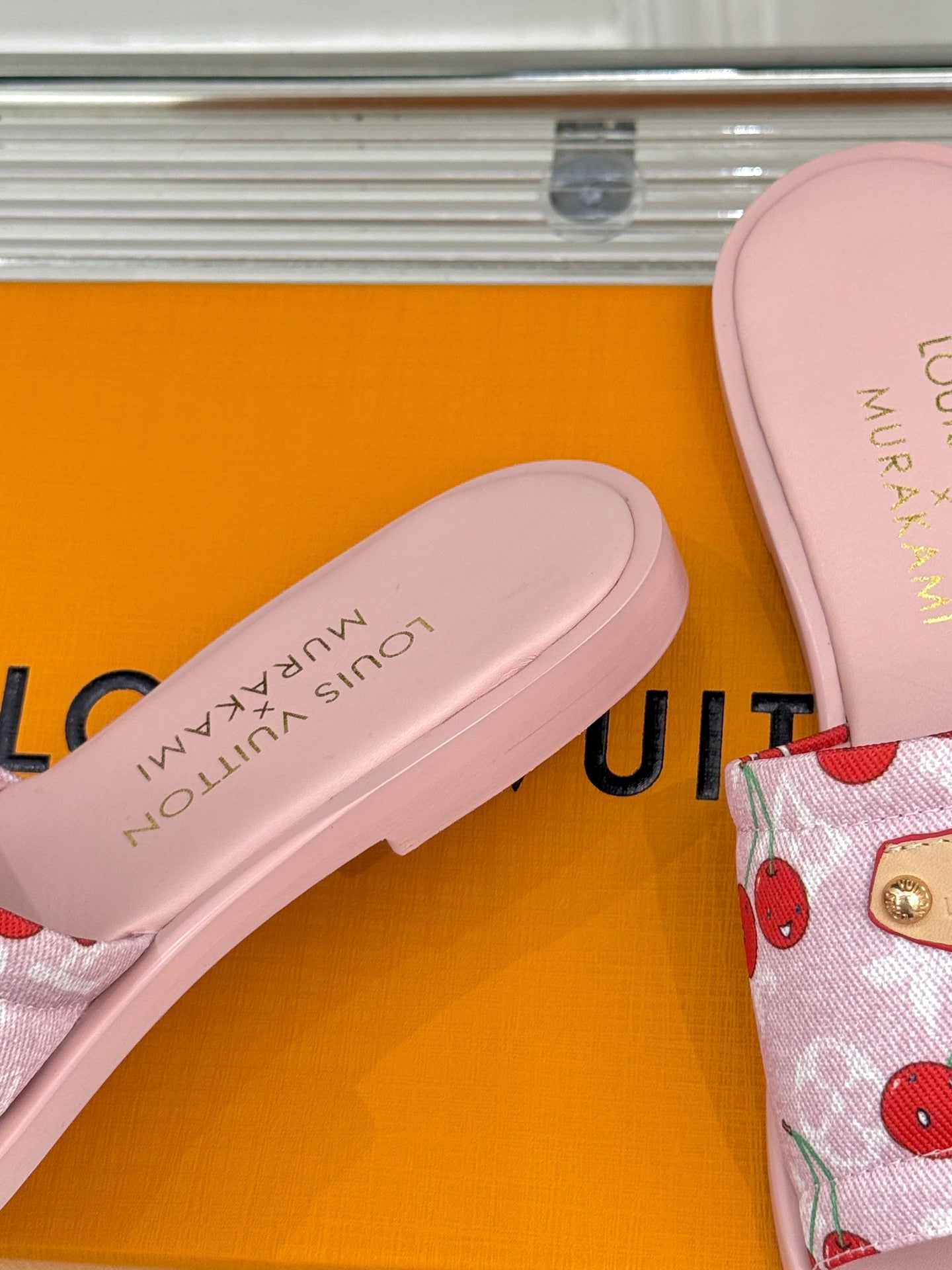Close-up of light pink slide sandal footbed and cherry-print fabric strap